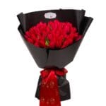Bouquet of 51 red tulips in dark wrapping with red satin ribbon