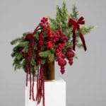 Majestic Red arrangement with pine and crimson ornaments in a gold vase